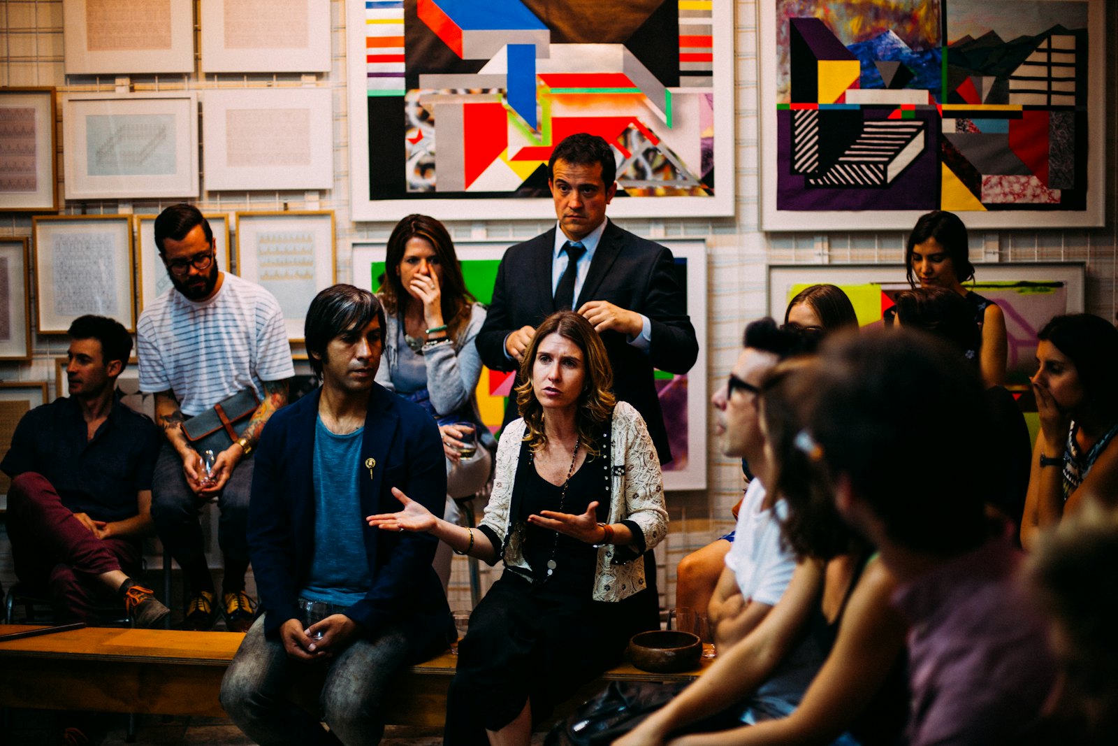 A room of people seated in loose rows at a community gathering, mid-discussion.